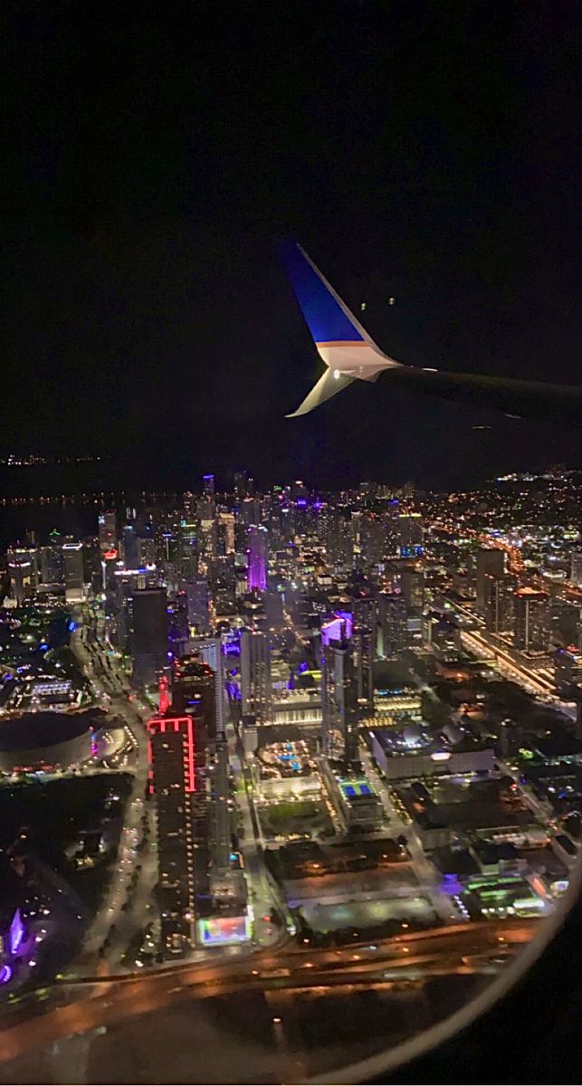 an airplane wing flying over a city at night