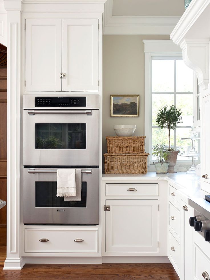 a kitchen with white cabinets and stainless steel ovens in the center, along with hardwood floors