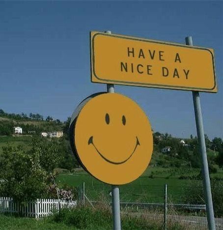 two yellow street signs sitting next to each other on top of a lush green field