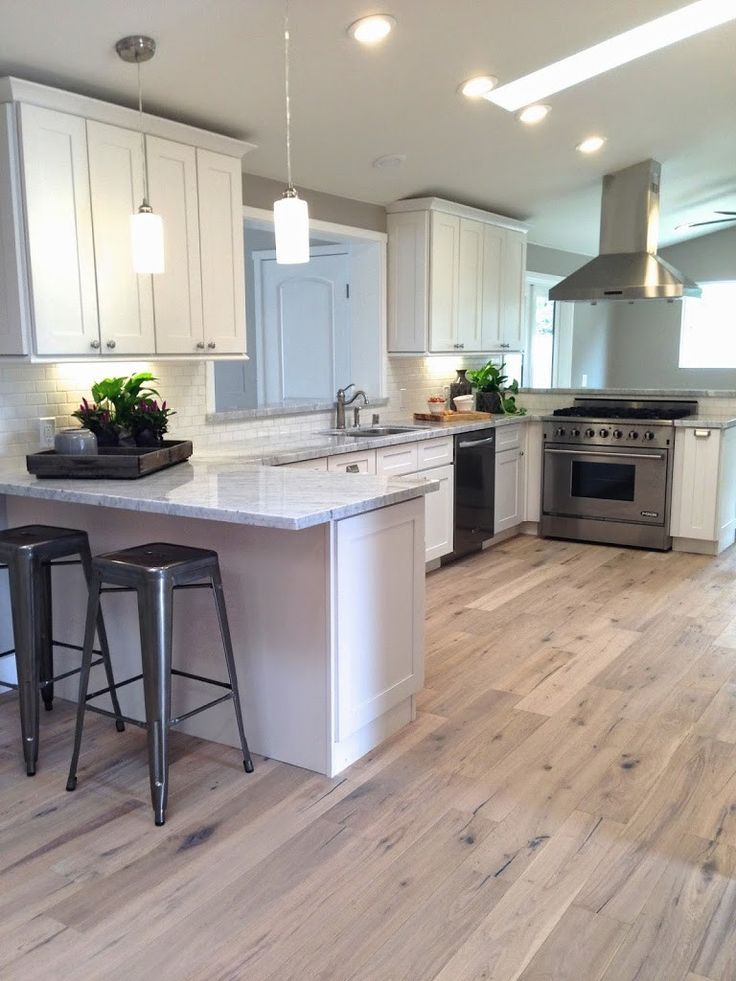 a kitchen with an island and two stools in the middle, white cabinets and stainless steel appliances