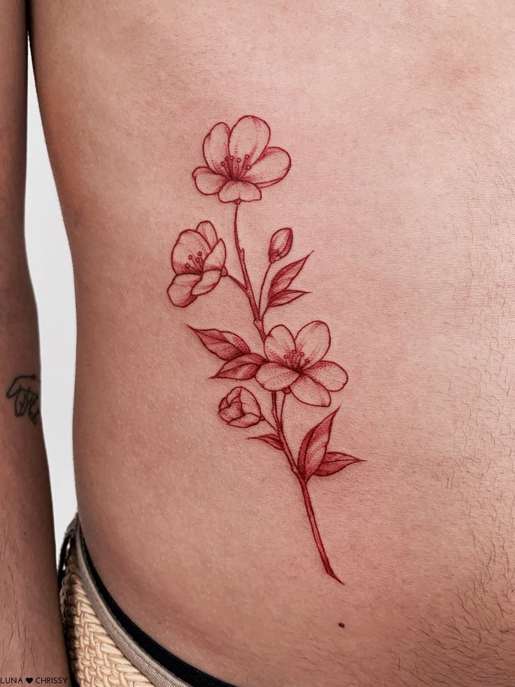 a close up of a person's stomach with flowers tattooed on the side,