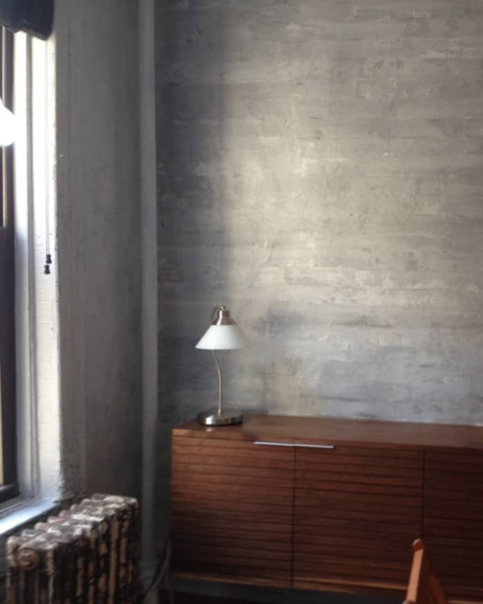 an empty room with a lamp on the table and a dresser in front of it