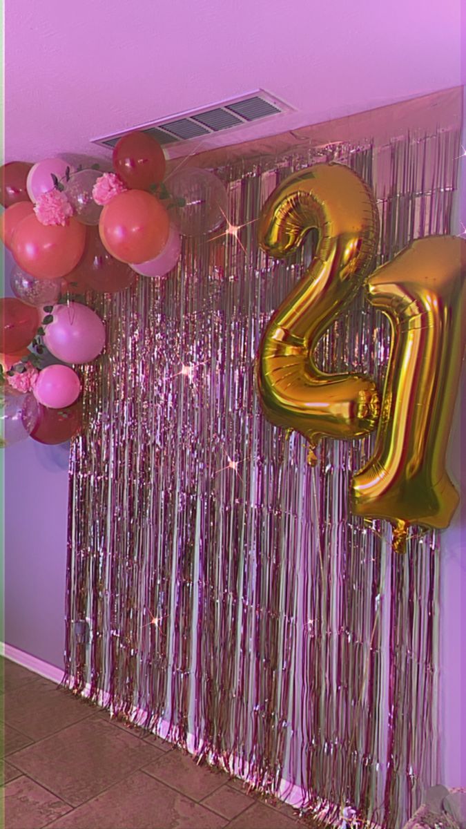 balloons and streamers in the shape of numbers are hanging on a wall with purple tinsel