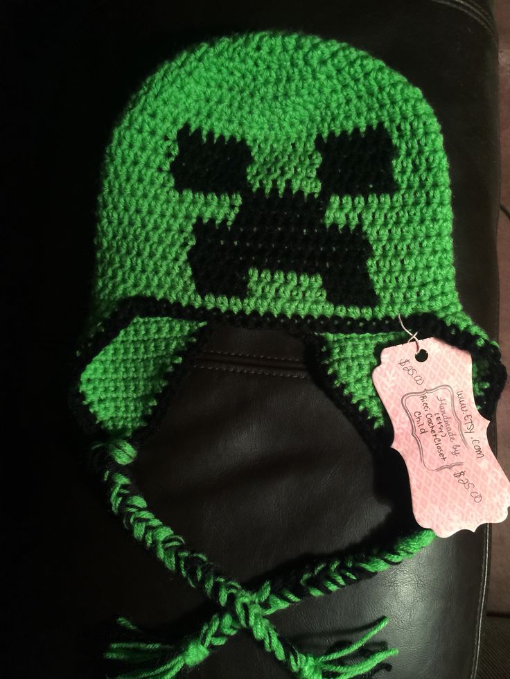 a crocheted hat with a green skull on it and a tag hanging from the front