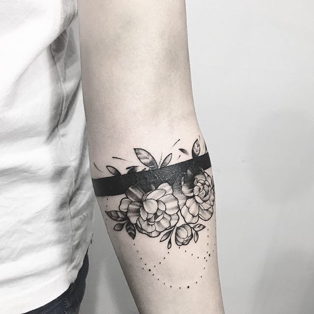 a black and white photo of a woman's arm with flowers on it