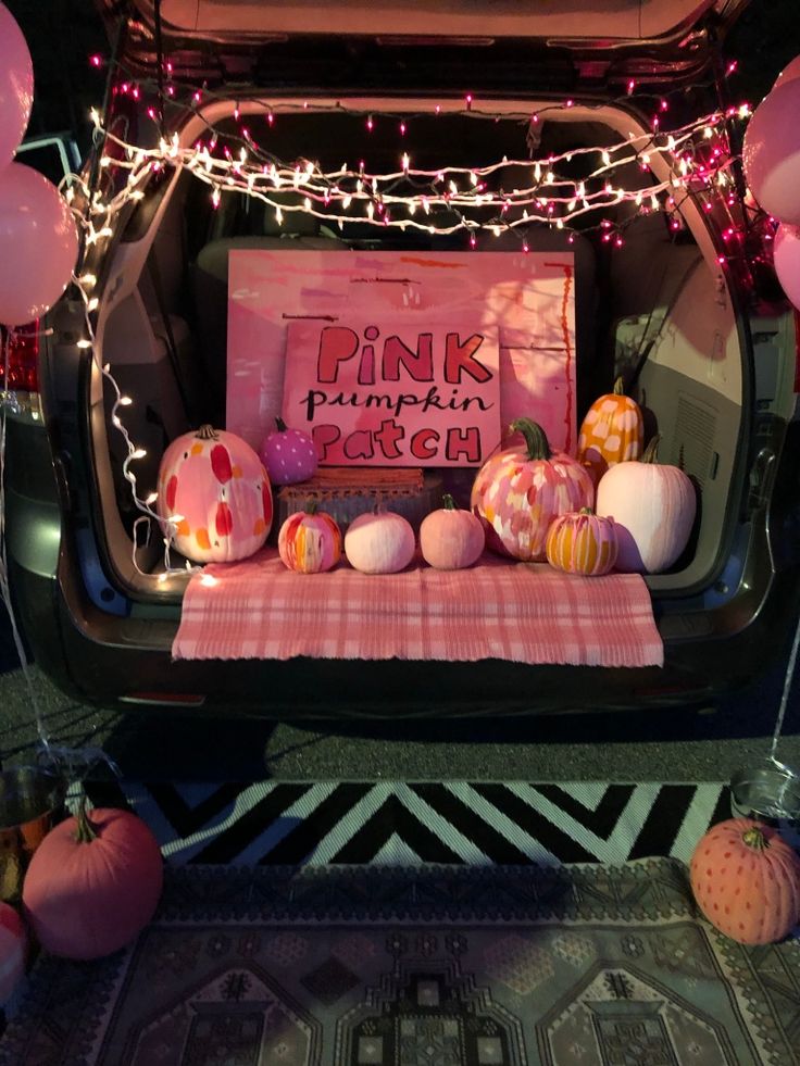 the trunk of a car decorated with pink pumpkins