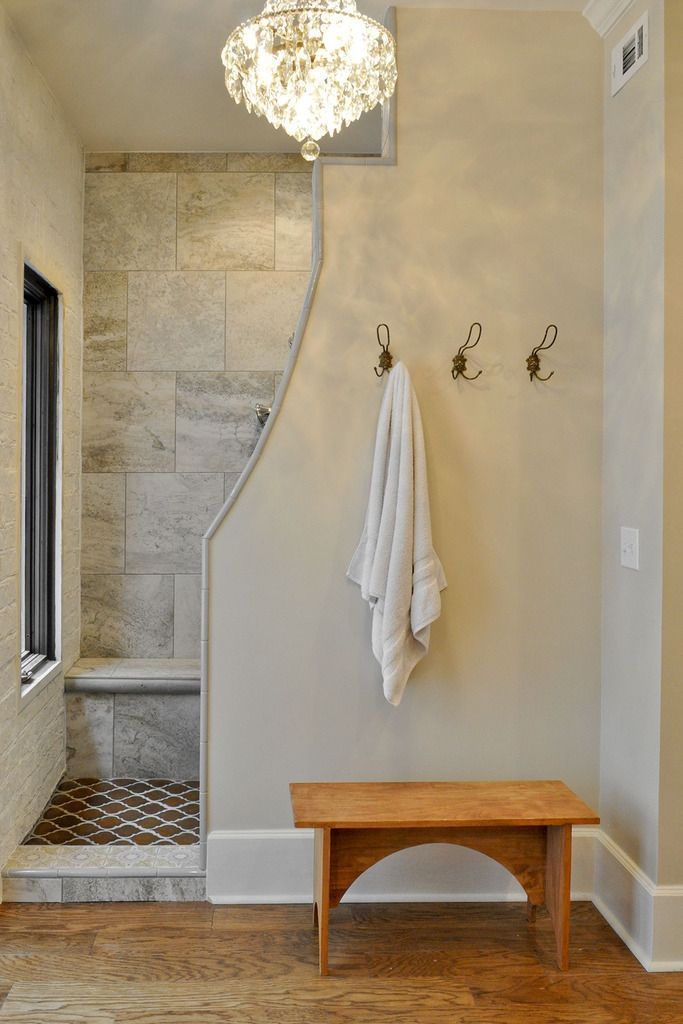 a bath room with a bench and a light hanging from the ceiling next to a shower