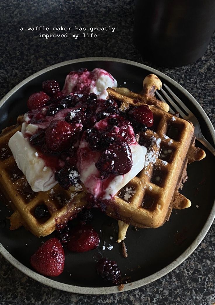 a plate with waffles, berries and ice cream sitting on top of it