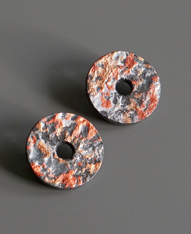 two rusted metal buttons sitting on top of a gray surface next to each other