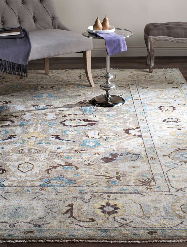 a large rug with an ornate design on the bottom and sides, in front of a gray couch