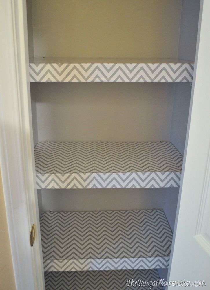 an empty closet with shelves painted white and gray chevrons on the bottom shelf