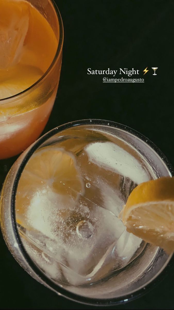 two glasses filled with drinks sitting on top of a black table next to each other