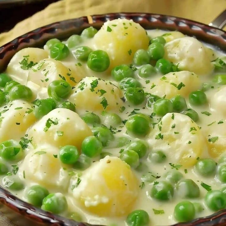 a bowl filled with peas and dumplings on top of a table