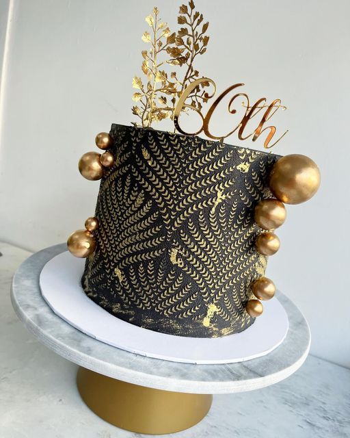 a black and gold cake with the letter c on top