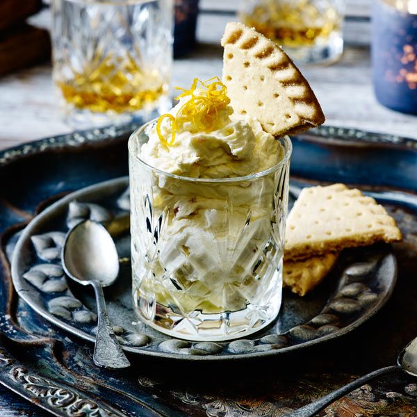 a glass with some food in it on a plate next to crackers and spoons