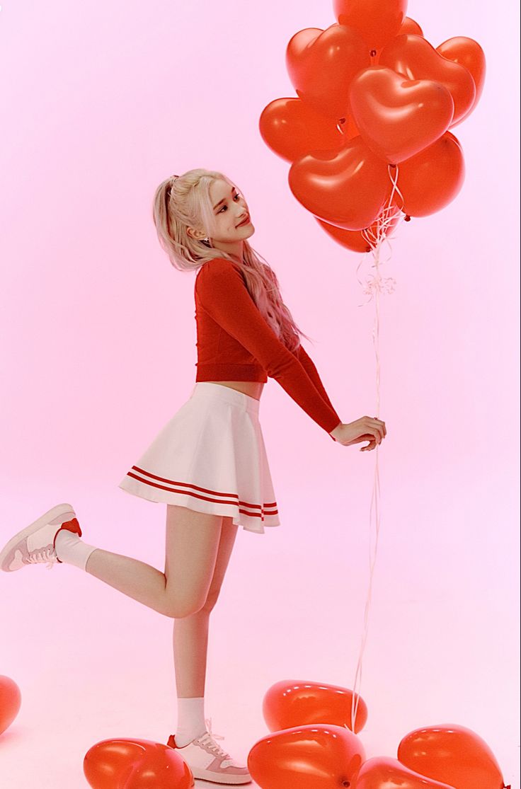 a woman in a red shirt and white skirt holding balloons