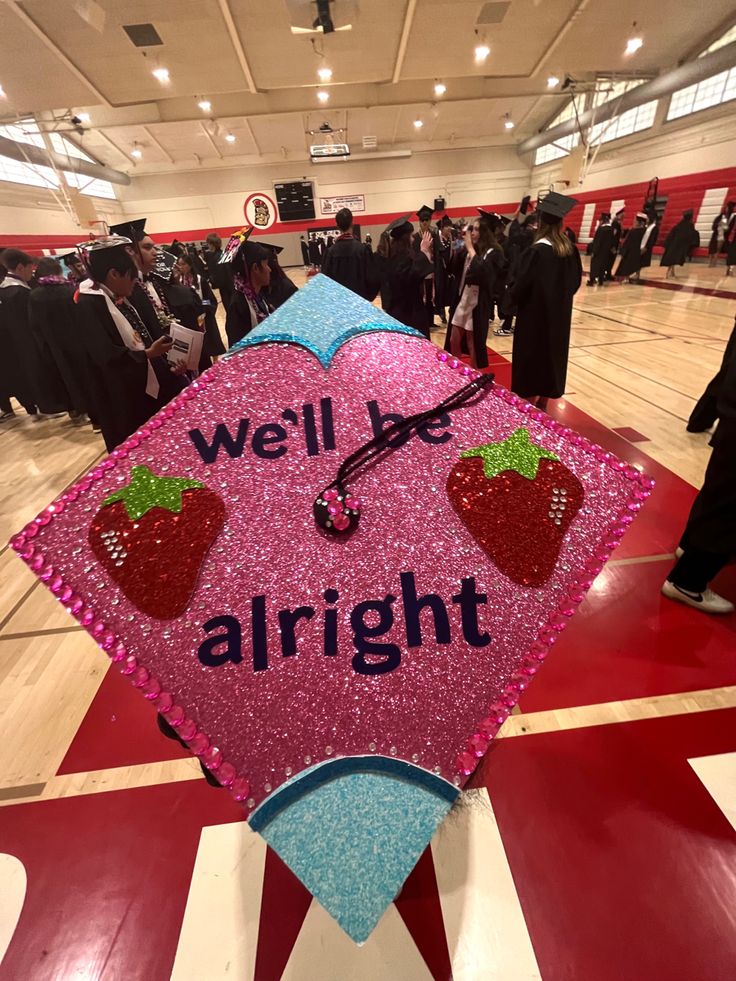 a pink and blue graduation cap with strawberries on it that says we'll be alright