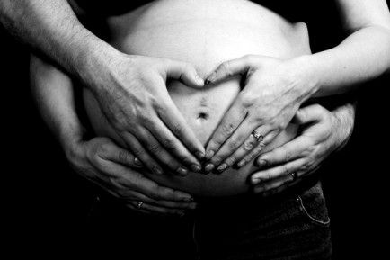 a pregnant woman is holding her hands in the shape of a heart on her belly