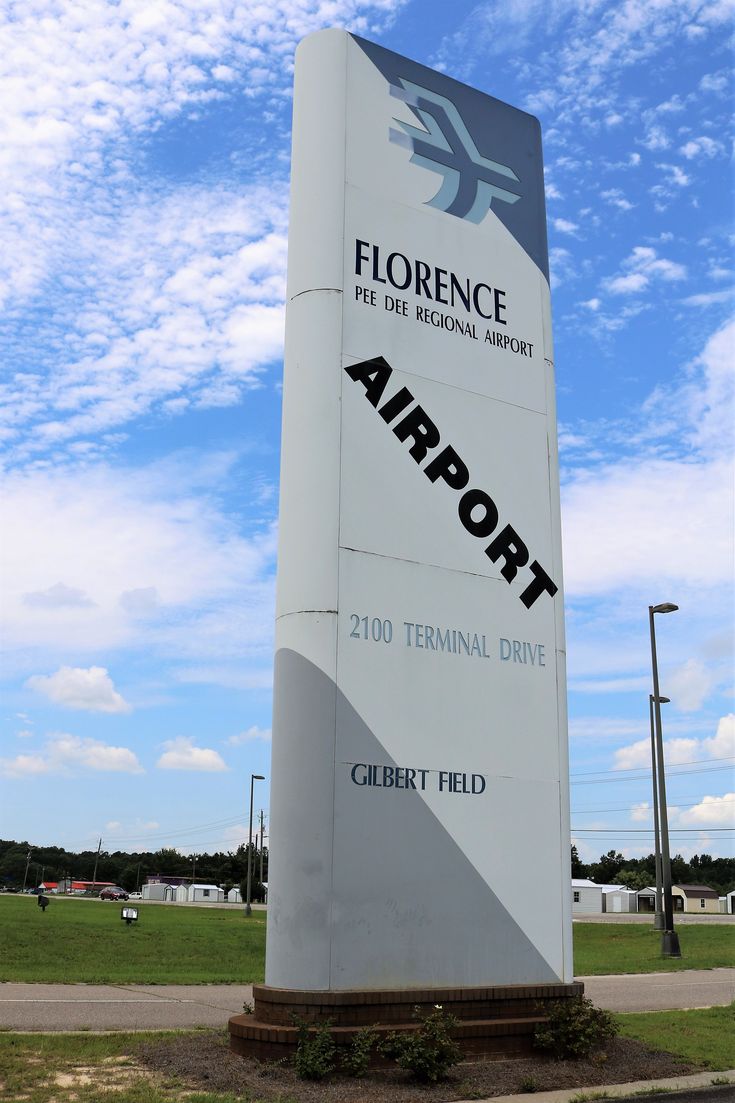 a large sign that is in the middle of a field with grass and blue sky behind it