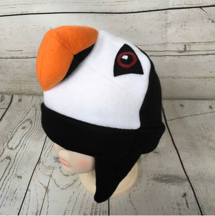 Adult and Kids Puffin Fleece Hat This is a bird hat made from black and white fleece. It features stuffed fleece beak and felt eyes. Hat Sizes: Baby: Approx. 20" around Child: Approx. 22" around Youth: Approx. 23 1/2" around Adult S/M: Approx. 24" around Adult M/L: Approx. 25" around Adult L/XL: Approx. 26" around Hat shown is a child size on a 18 1/2" (47cm) head. Care: Machine wash on cool or warm; dry on low. Turnaround time varies throughout the year but is usually 1-3 business days. Standar Kids Animal Hats, Skunk Costume, Bird Hat, Puffin Bird, Best Winter Hats, Felt Eyes, Squirrel Gift, Pink Dinosaur, Toddler Winter