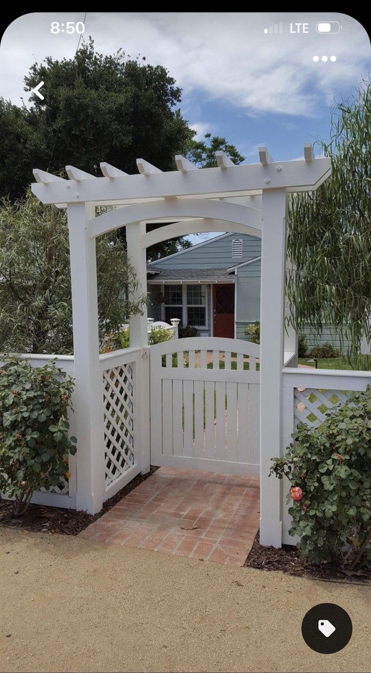 a white fence with a brick walkway leading to the front door and side yard area