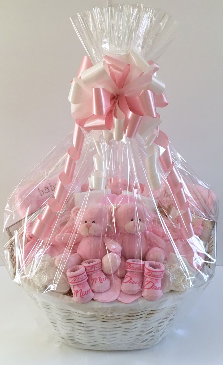 a basket filled with pink teddy bears wrapped in cellophane and sitting on top of a table