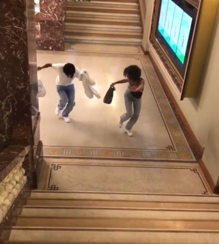 two people are walking down the stairs in front of a tv screen and holding hands with each other