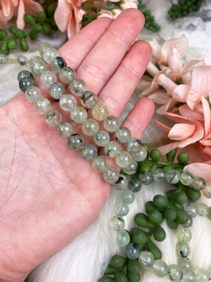 Carry your protective energies with you in style with this simple Epidote in Prehnite bracelet! Crystals are full of natural energy, each one of which has specific properties or meanings to help in your daily life. Whether you are looking to enhance your loving energies, protect your positive energy, or reach your goals, there is a crystal out there to help you. You will receive ONE prehnite bracelet that is intuitively chosen for you.Approx Bead Size: 7-8mmApprox Size 6-6.5" around. Colors and Holistic Green Bracelets With Gemstone Beads, Green Gemstone Crystal Bracelet For Meditation, Green Hand-strung Bracelet For Meditation, Green Spiritual Crystal Bracelet For Healing, Spiritual Green Crystal Bracelet For Healing, Spiritual Green Crystal Bracelet With Gemstone Beads, Green Natural Stone Beaded Bracelets For Healing, Adjustable Green Moss Agate Bracelet, Green Natural Stone Beaded Bracelets For Meditation