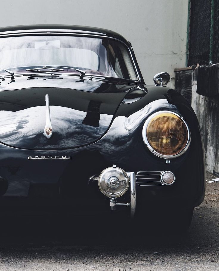 an old black sports car parked in front of a building