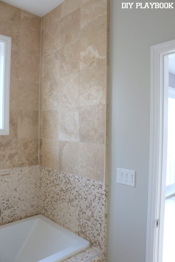 a bath tub sitting under a window next to a wall mounted faucet in a bathroom