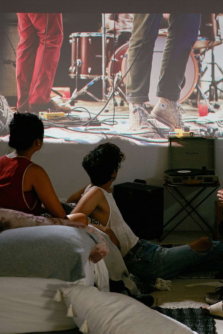 three people sitting on the floor in front of a projector screen with musical instruments