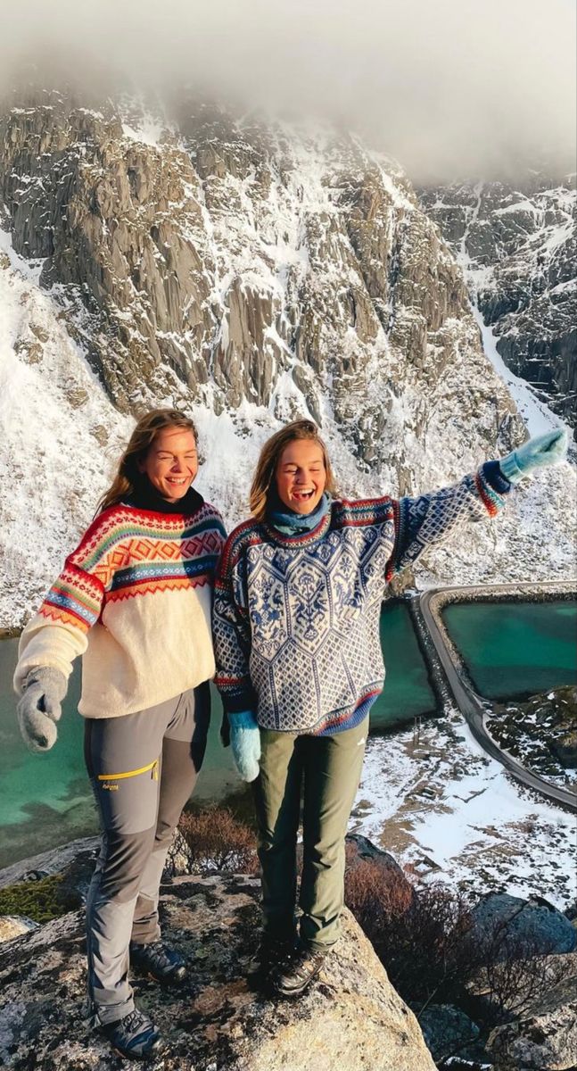 two women standing on top of a mountain with their arms in the air