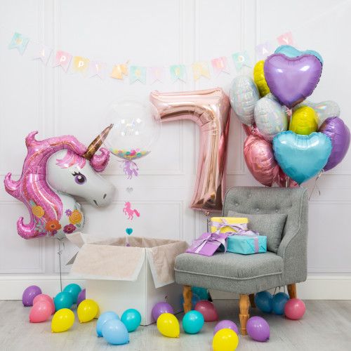 a unicorn themed birthday party with balloons and streamers on the floor, including an armchair