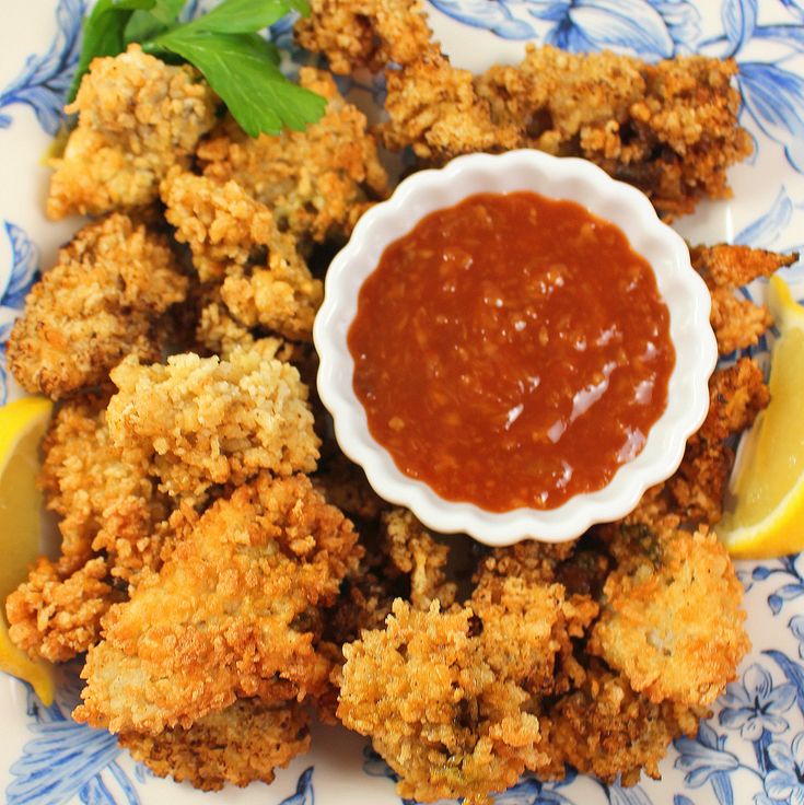 fried food with sauce and lemon wedges on a blue and white plate, ready to be eaten