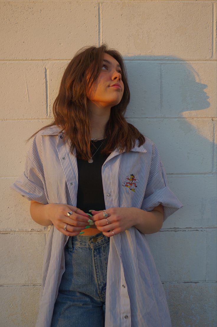 a woman standing in front of a white brick wall with her hands on her hips