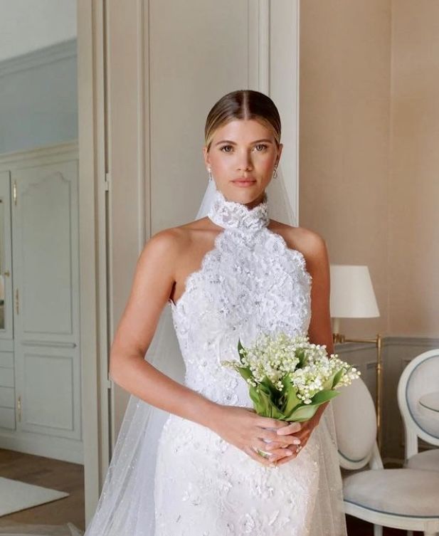 a woman in a wedding dress holding a bouquet of flowers and posing for the camera