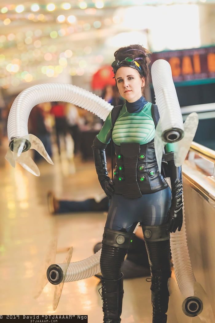 a woman dressed in black and green is standing next to an escalator