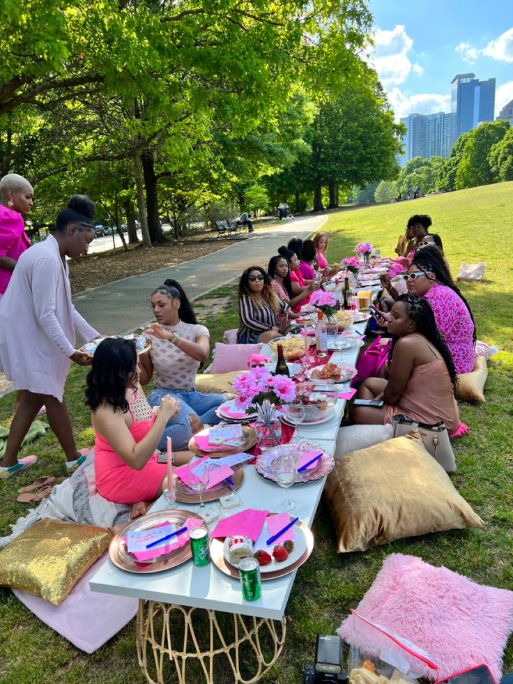 a group of people sitting at a picnic table eating cake and drinking watermelon