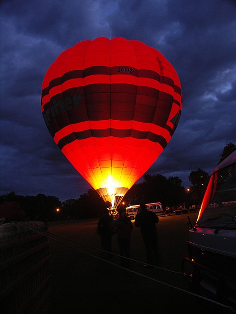 two people standing in front of a hot air balloon with the lights on at night