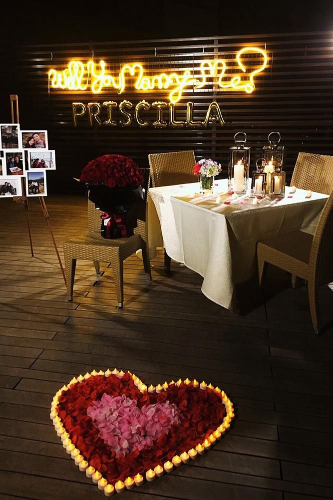 a heart shaped flower arrangement on the ground in front of a restaurant with tables and chairs