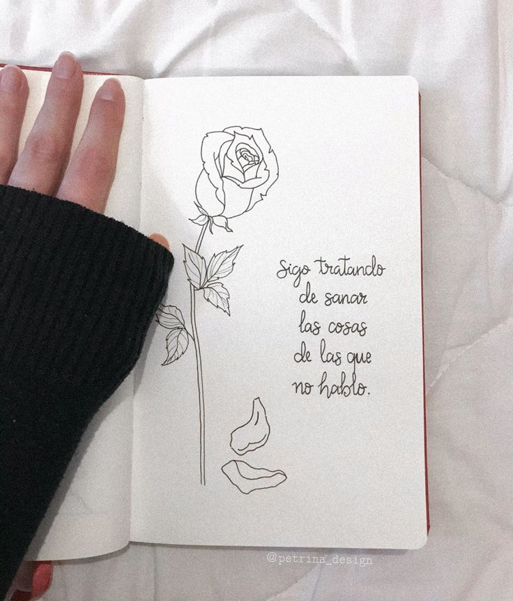 a hand holding an open notebook with a rose on the page and some words written in cursive writing