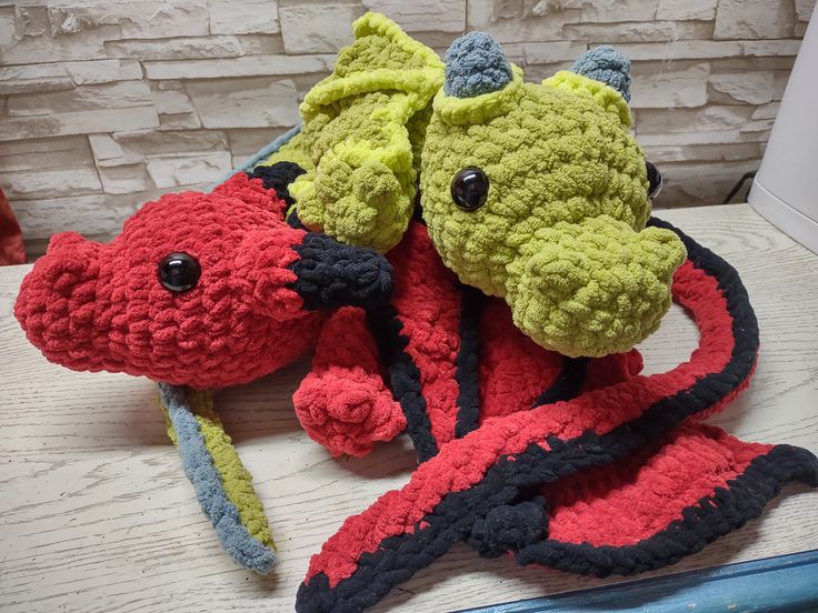 two crocheted stuffed animals sitting next to each other on top of a table