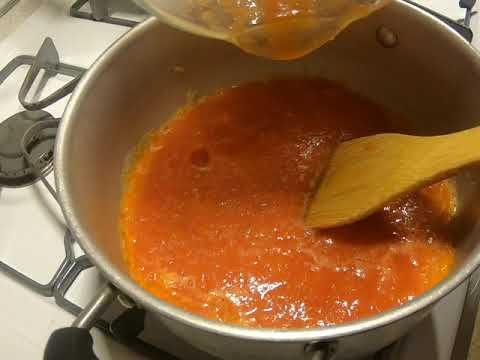 a wooden spoon in a pot on top of a stove with red sauce and cheese