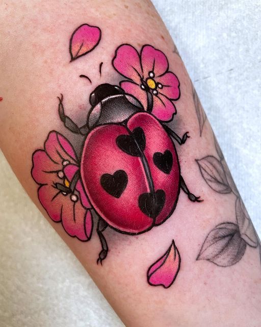 a ladybug tattoo with hearts and flowers on it