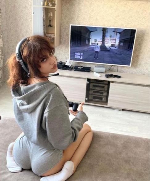 a woman sitting on the floor in front of a flat screen tv with headphones