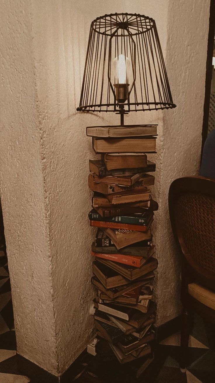 a lamp sitting on top of a stack of books next to a wall filled with books