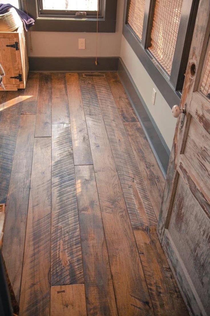 an empty room with wood flooring and a wooden door in the center, looking out to outside