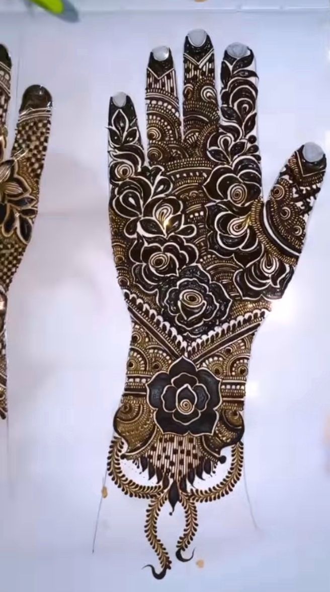 an intricately designed hand is displayed on a white surface with gold and black designs