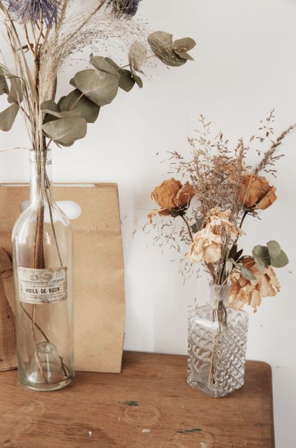 two vases filled with flowers on top of a wooden table next to a bag