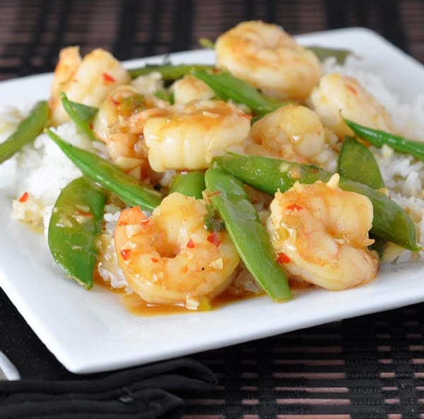 a white plate topped with rice and shrimp next to green beans on top of it